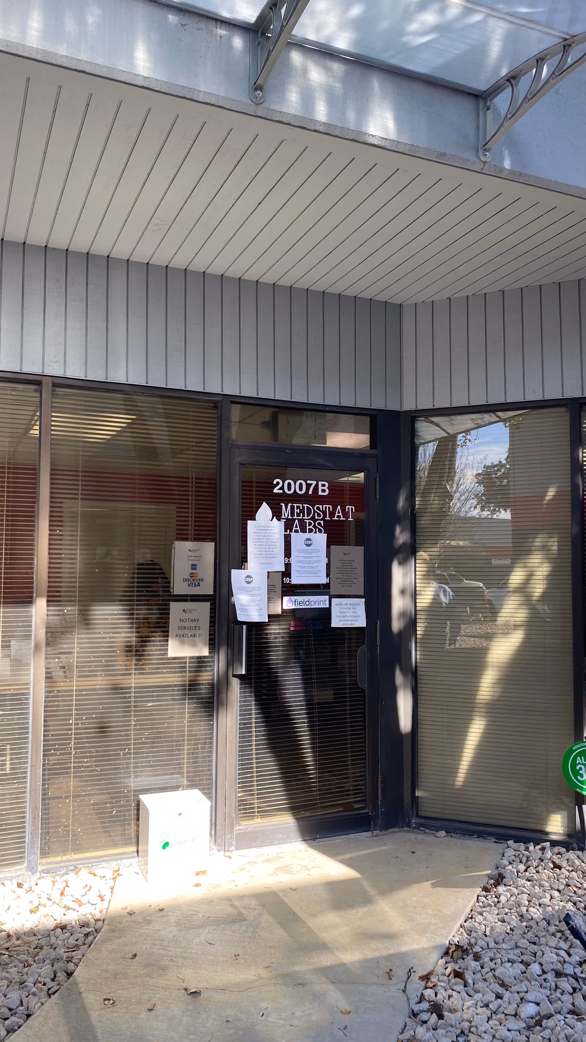 Exterior entrance to Medstat Labs with glass doors and posted notices.