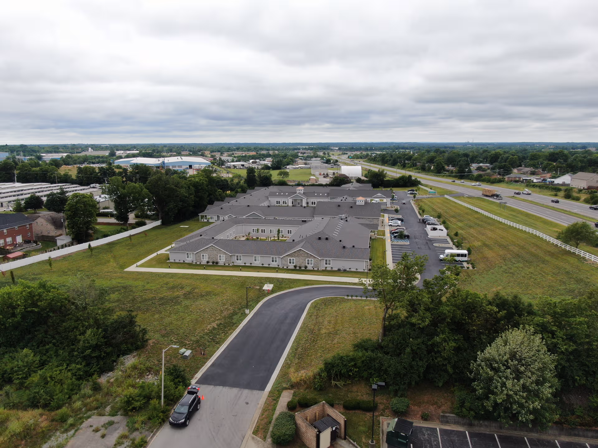 Aerial view of Cedarhurst Senior Living facility with grey roofs, parking lot, and surrounding fields.