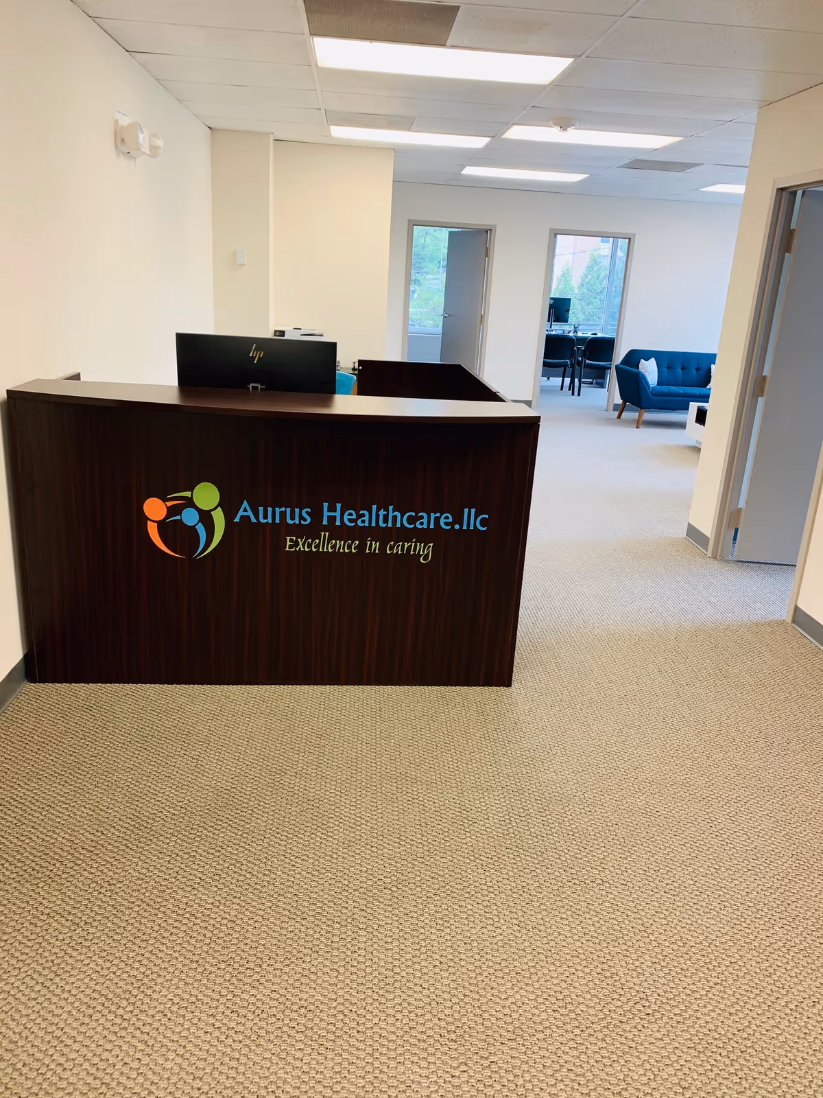 Reception desk with Aurus Healthcare.llc logo in a bright interior lobby.