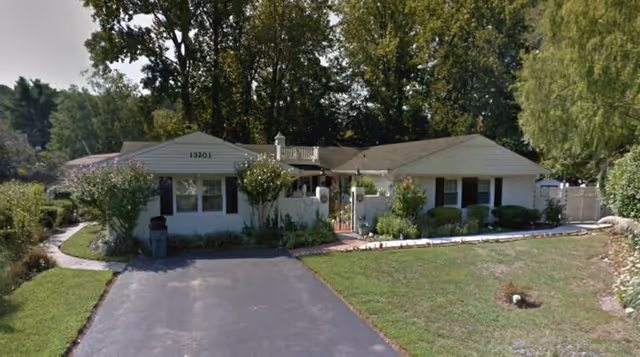 Front exterior of Caring Hearts and Hands Assisted Living with driveway and greenery.