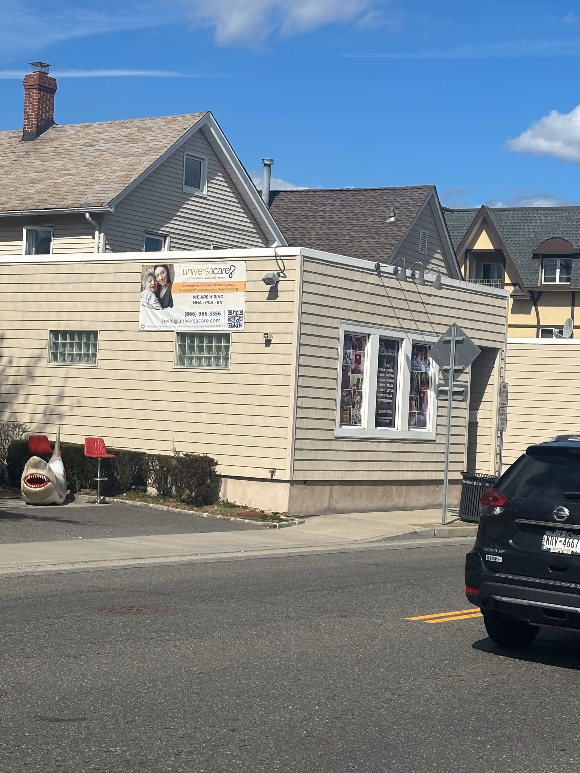 Exterior view of UniversaCare of Nassau building with banner, street, and parked car.