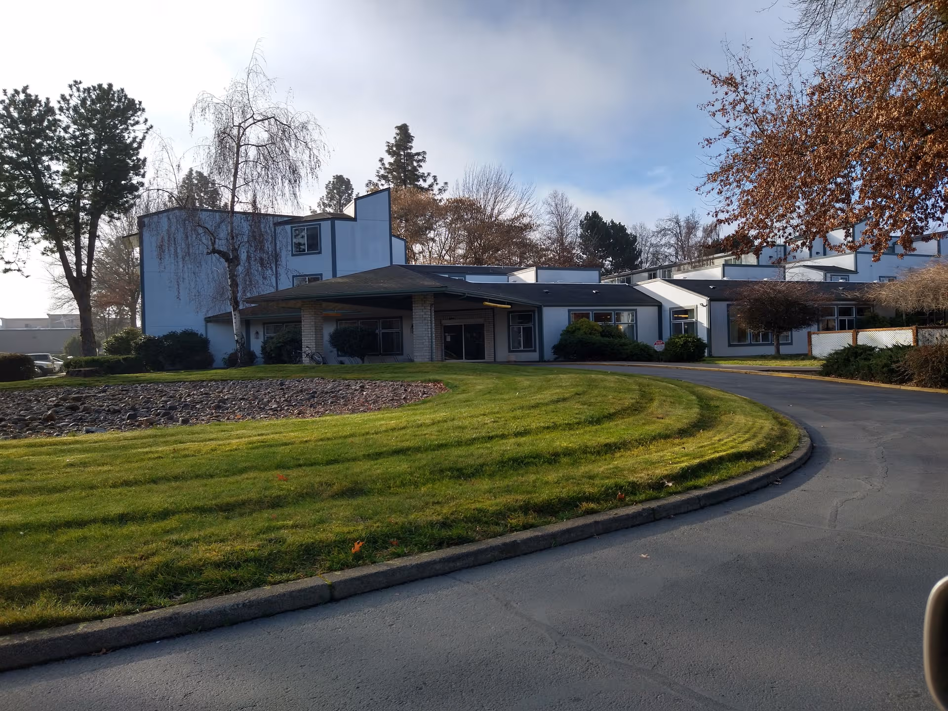 Front exterior of Rogue River Estates Retirement with curved driveway and green lawn.