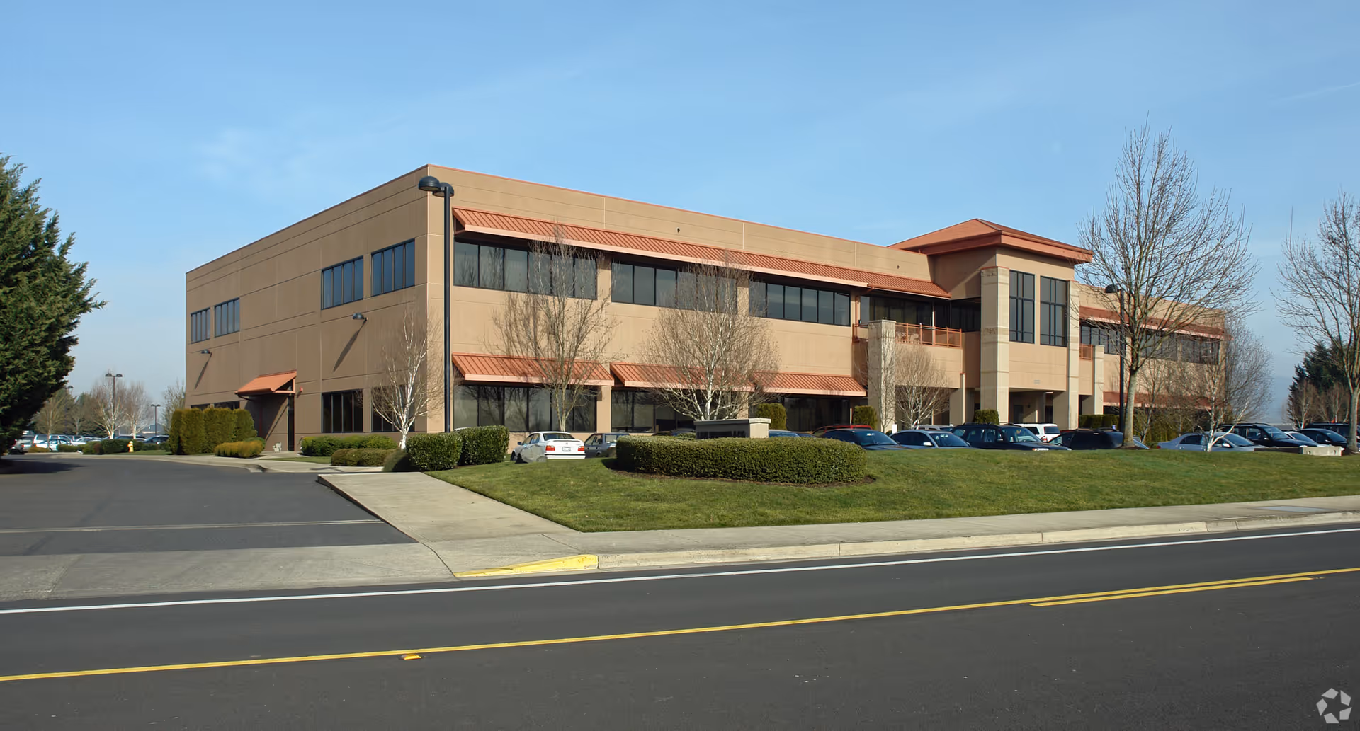 Two-story beige facility exterior with red awnings and a parking lot in front