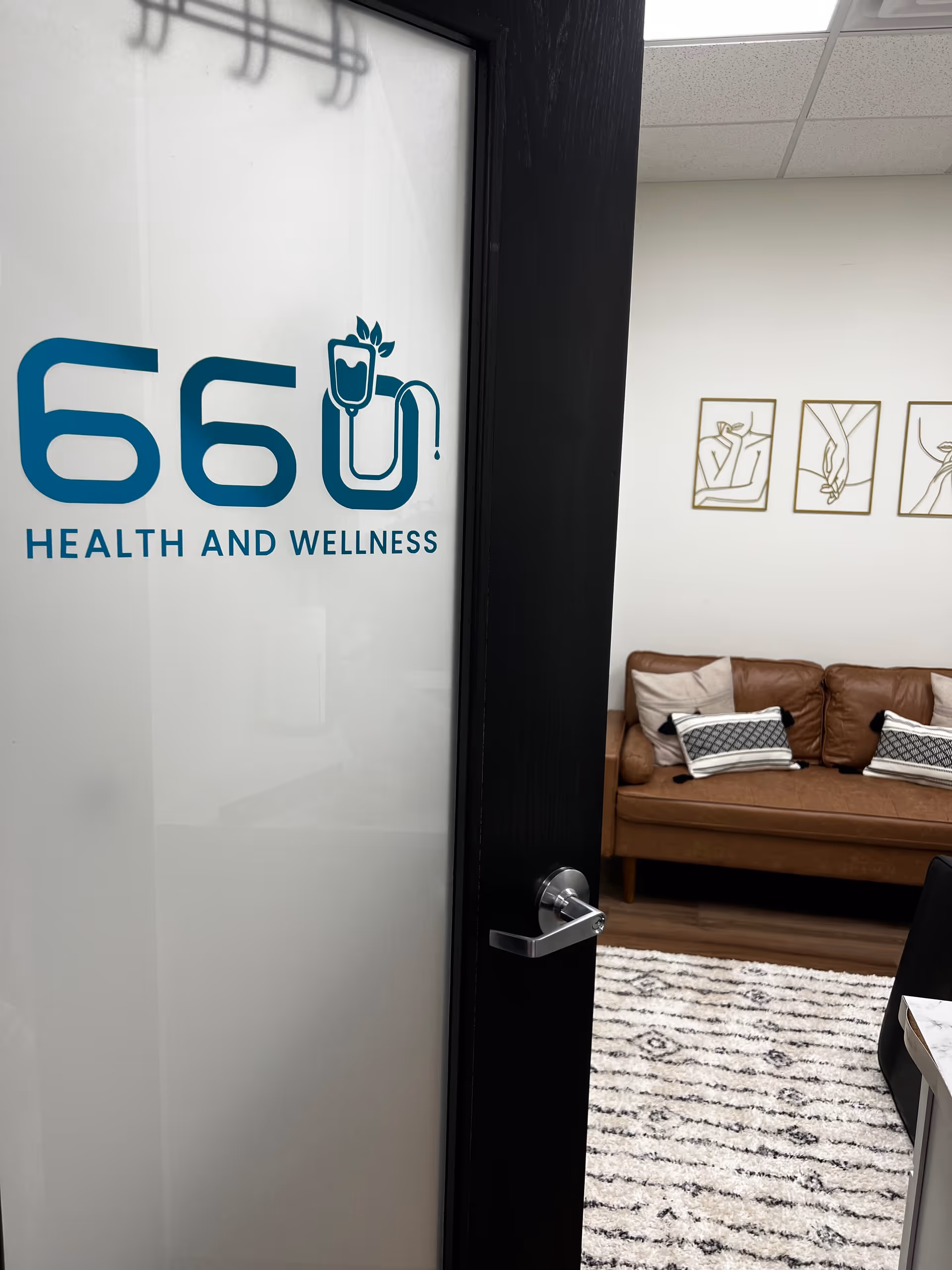 Glass door shows the 66 Health and Wellness logo; interior lounge with sofa and wall art.