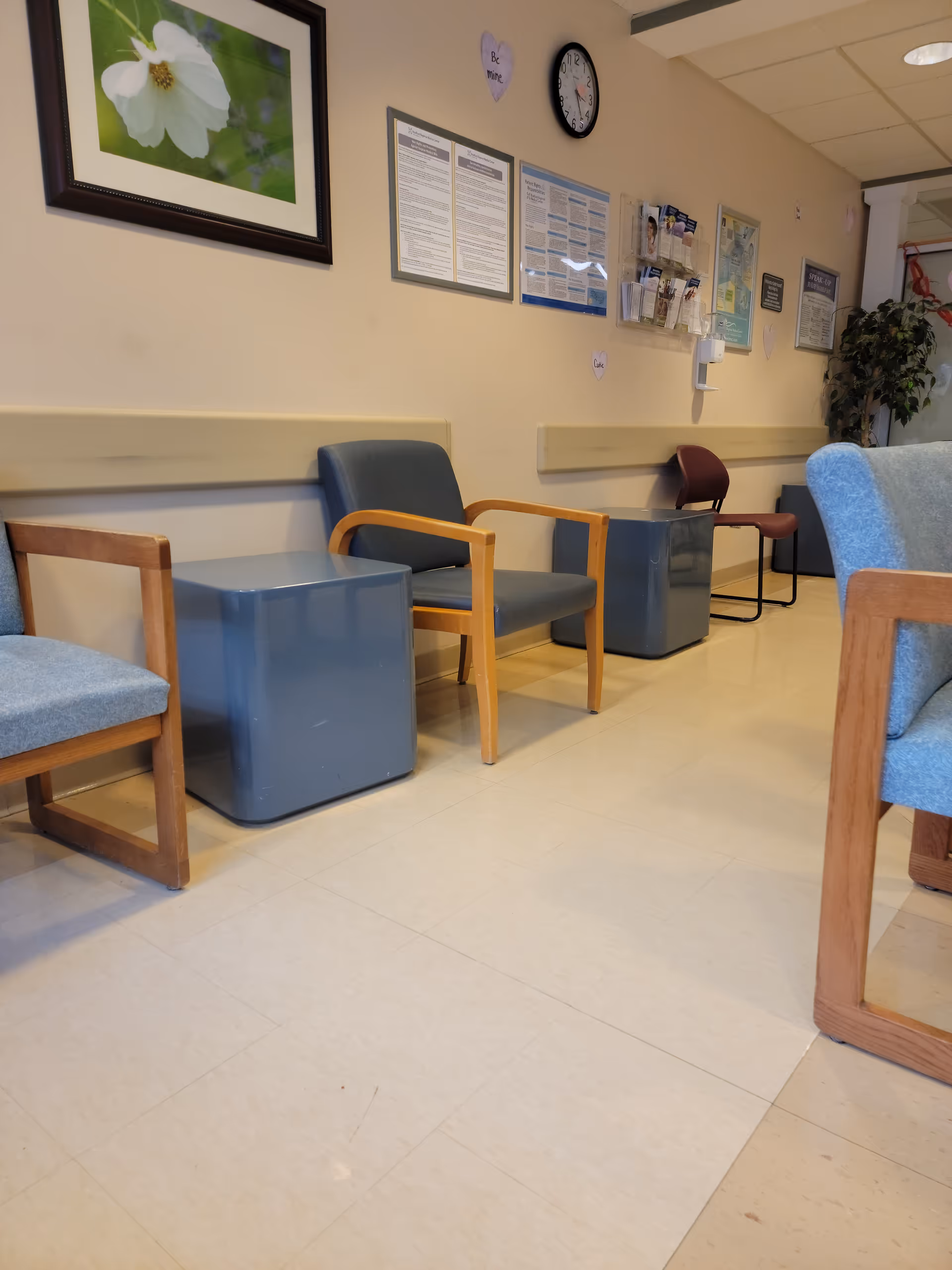 Waiting area in a medical center with blue chairs and wall posters.