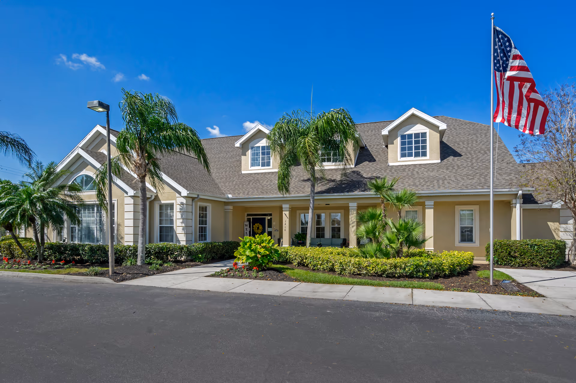 Front view of Brookdale Cape Coral senior living facility with entrance, landscaping, and American flag.