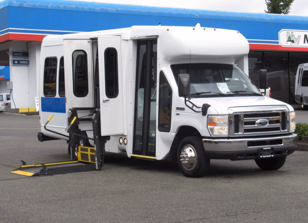 White shuttle bus with ramp deployed parked in front of a Good Hands Home Care building