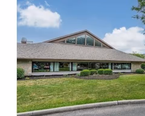 Front exterior view of The Village of Westerville senior living facility with windows and lawn.