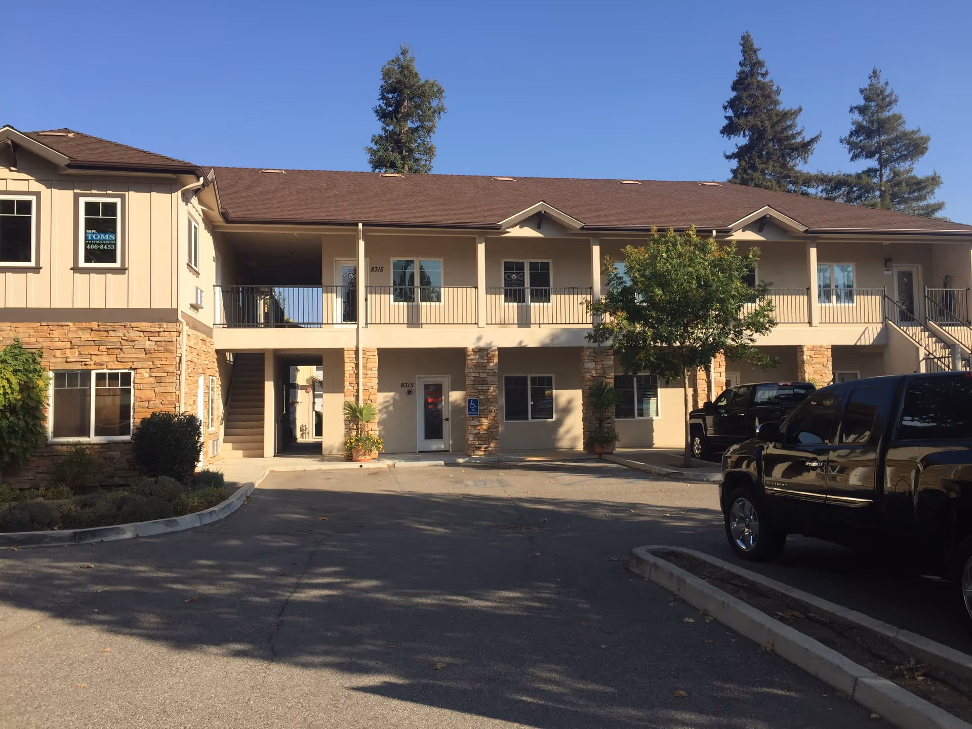 Two-story beige senior living facility with parking lot and landscaping in front.