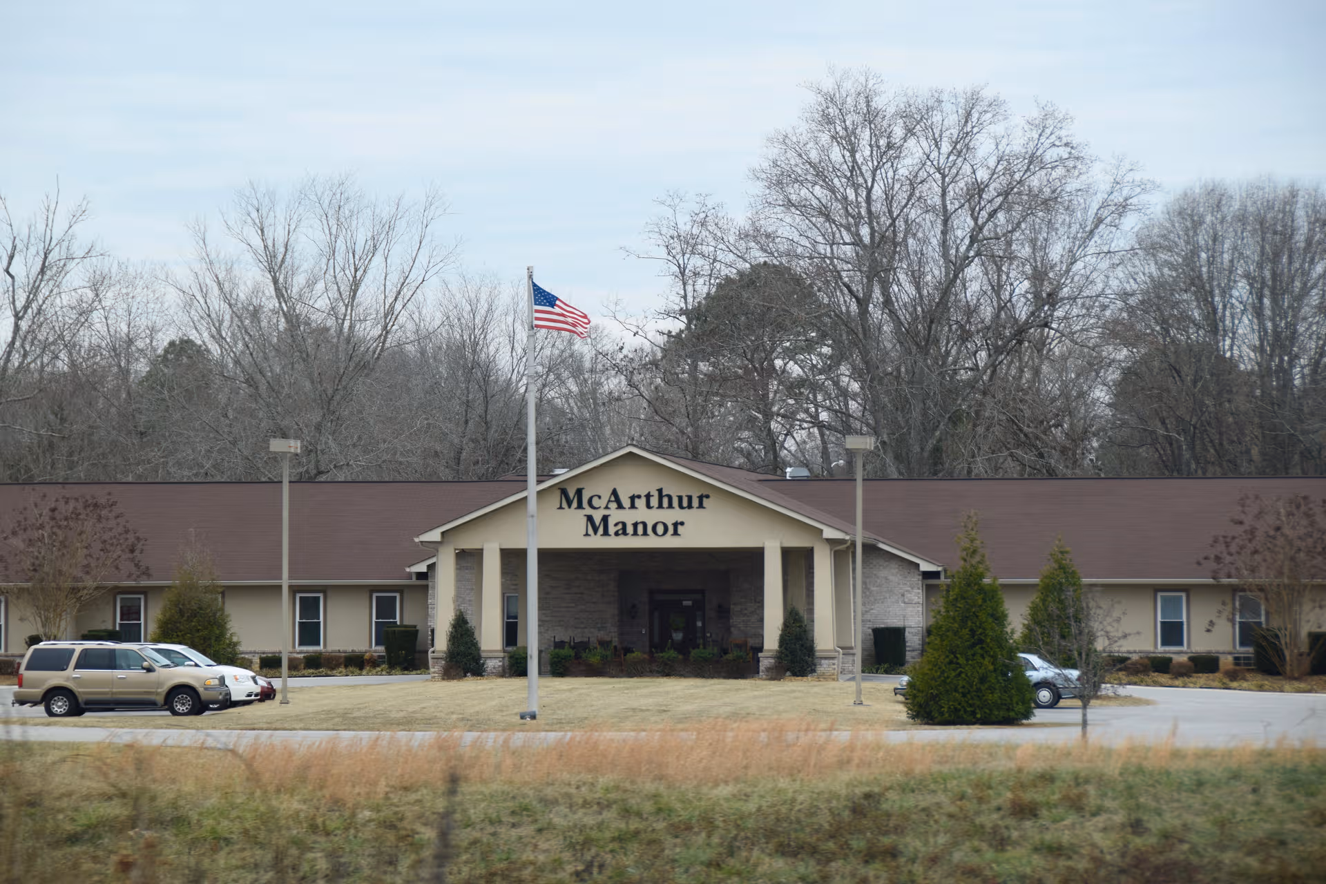 Front view of McArthur Manor Assisted Living with entrance canopy and American flag