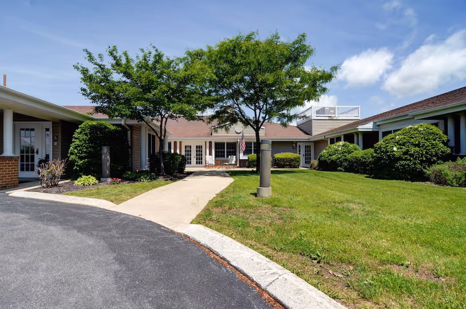 Daytime exterior view of Celebration Villa of Altoona with a manicured lawn and trees.