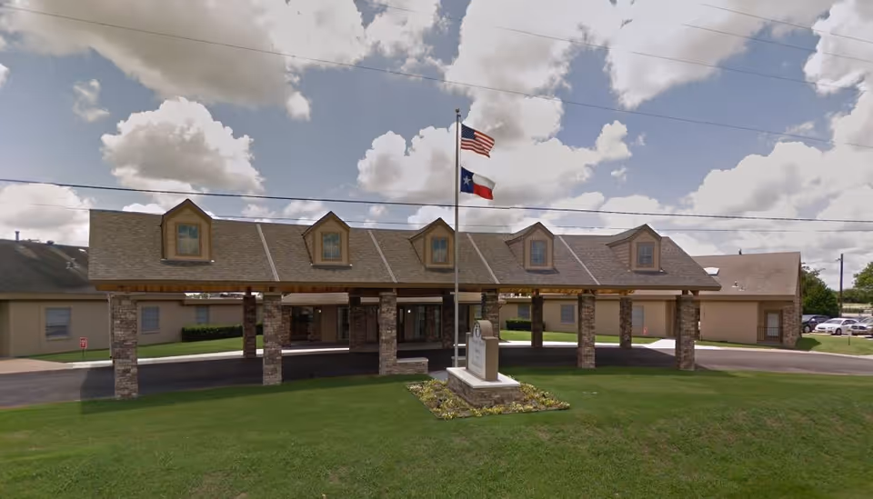 Exterior view of Pleasant Manor Health & Rehabilitation Center with flagpole and covered entrance.