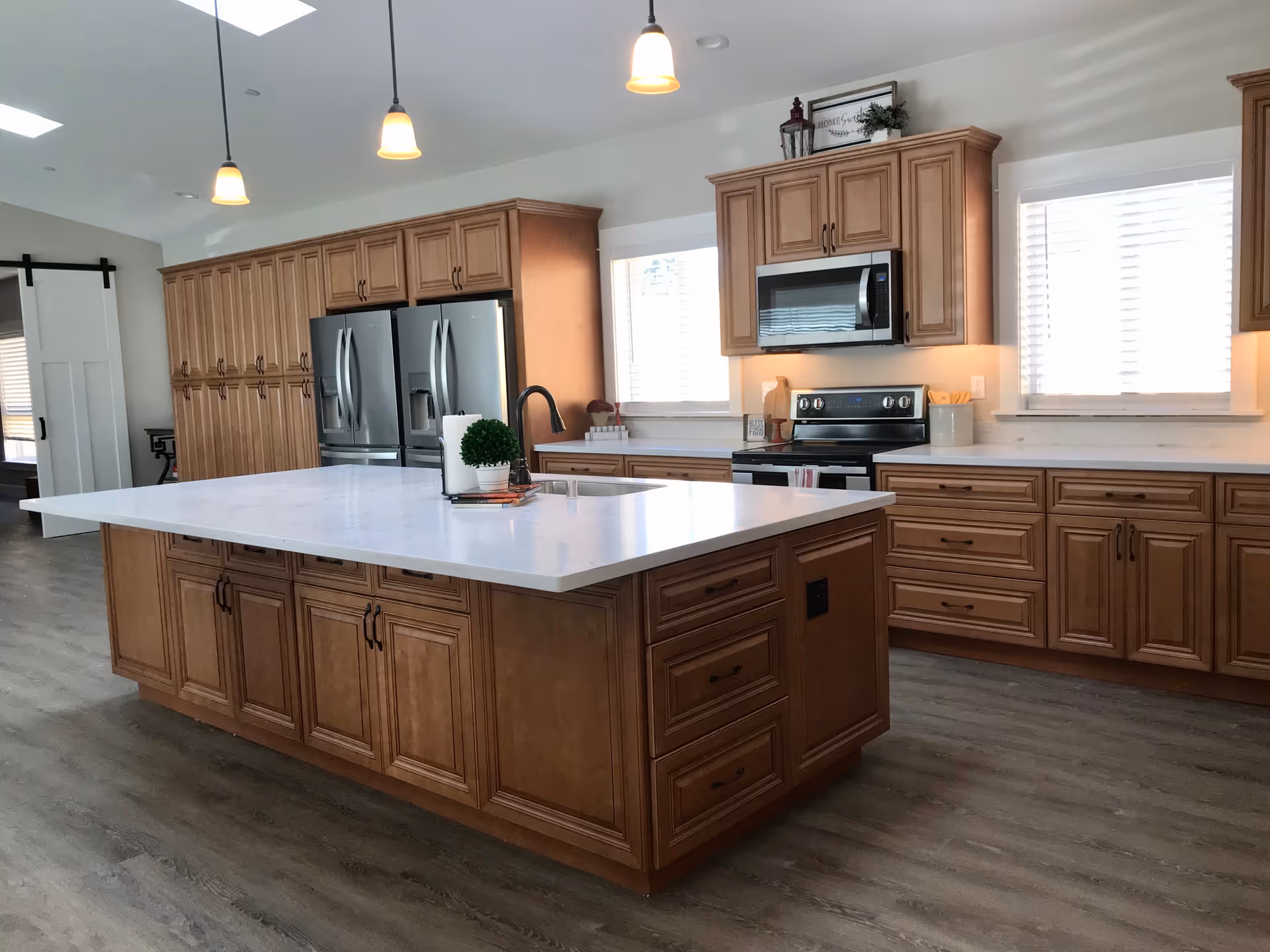 Bright modern kitchen with large island, wooden cabinets, and stainless-steel appliances.