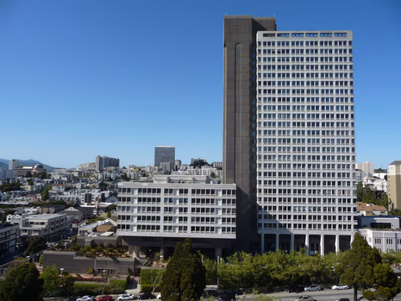Exterior view of a tall modern building with surrounding low-rise cityscape.