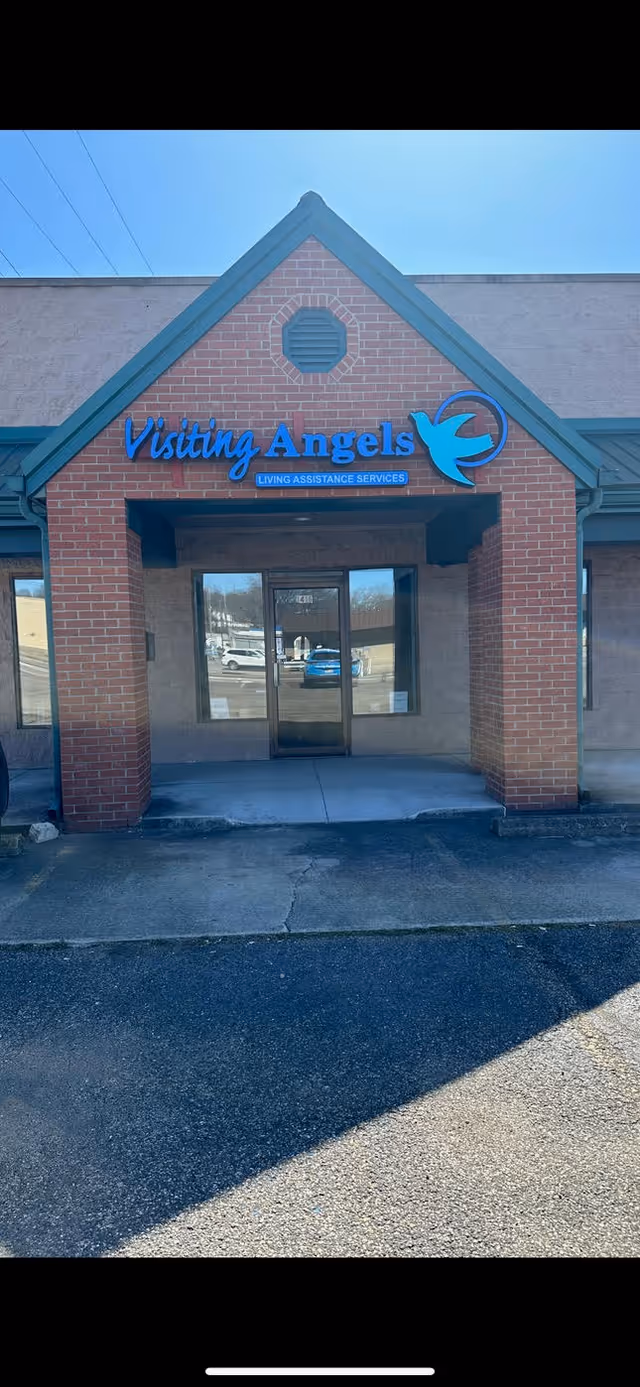 Brick building entrance for Visiting Angels in Portsmouth with a blue sign and glass doors.