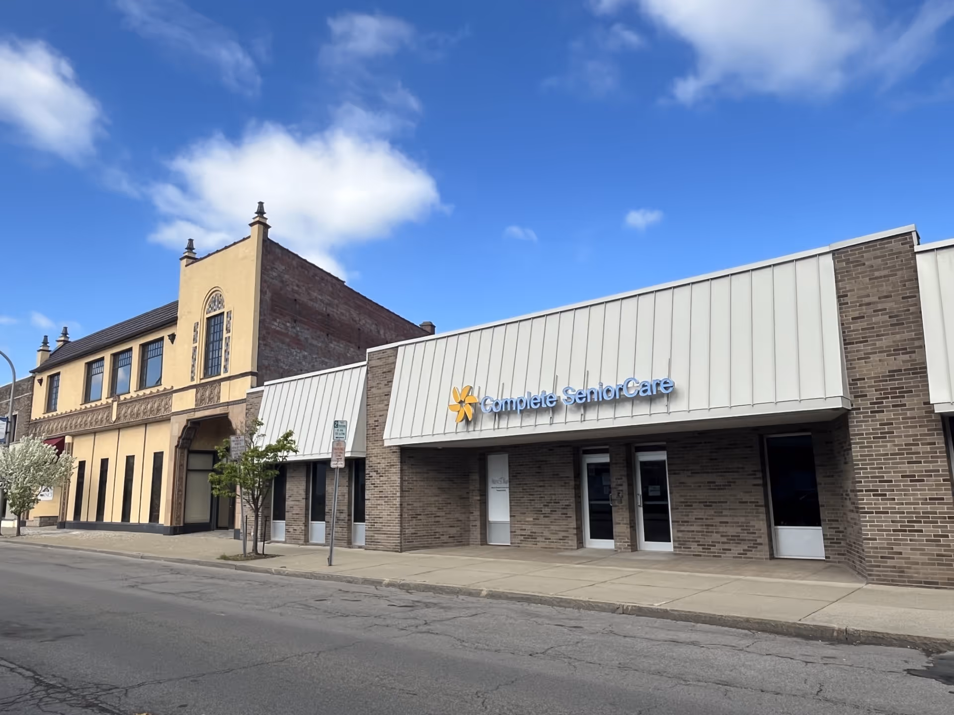 Street view of Complete Senior Care building with brick storefront and blue sky.