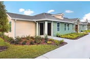 Exterior view of Quail Run Health Care Center with pastel siding, landscaping, and walkway.
