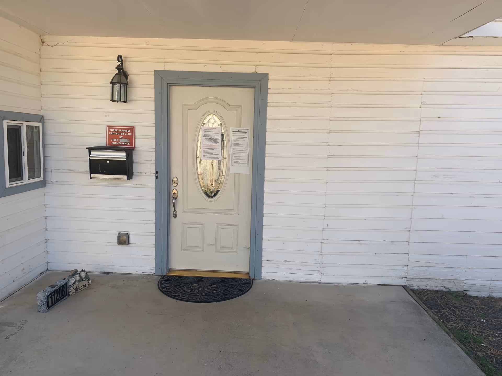 White exterior wall with a front door, porch, mailbox, and welcome mat.