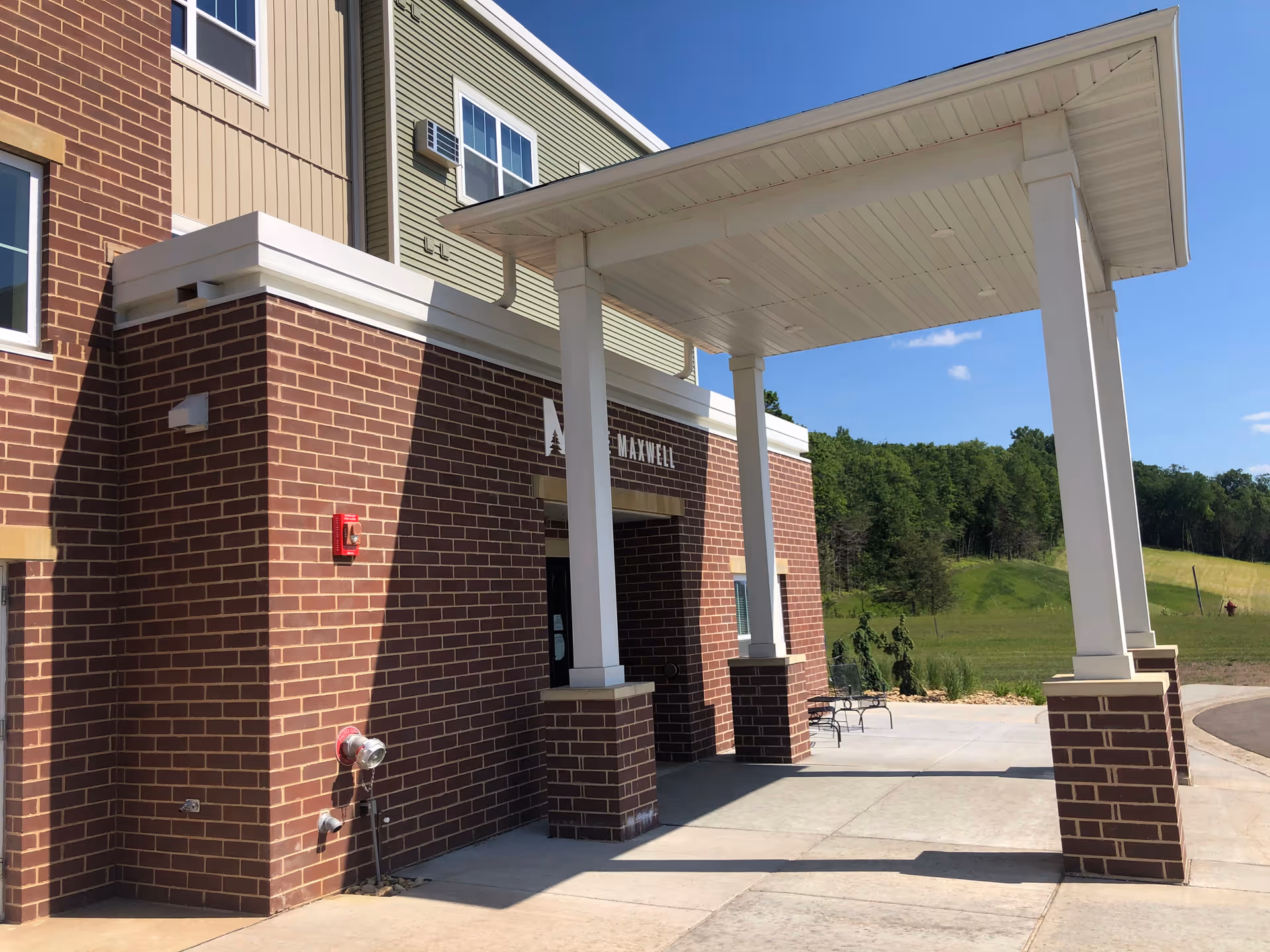 Exterior view of The Maxwell senior living facility entrance with brick walls and a covered porch.