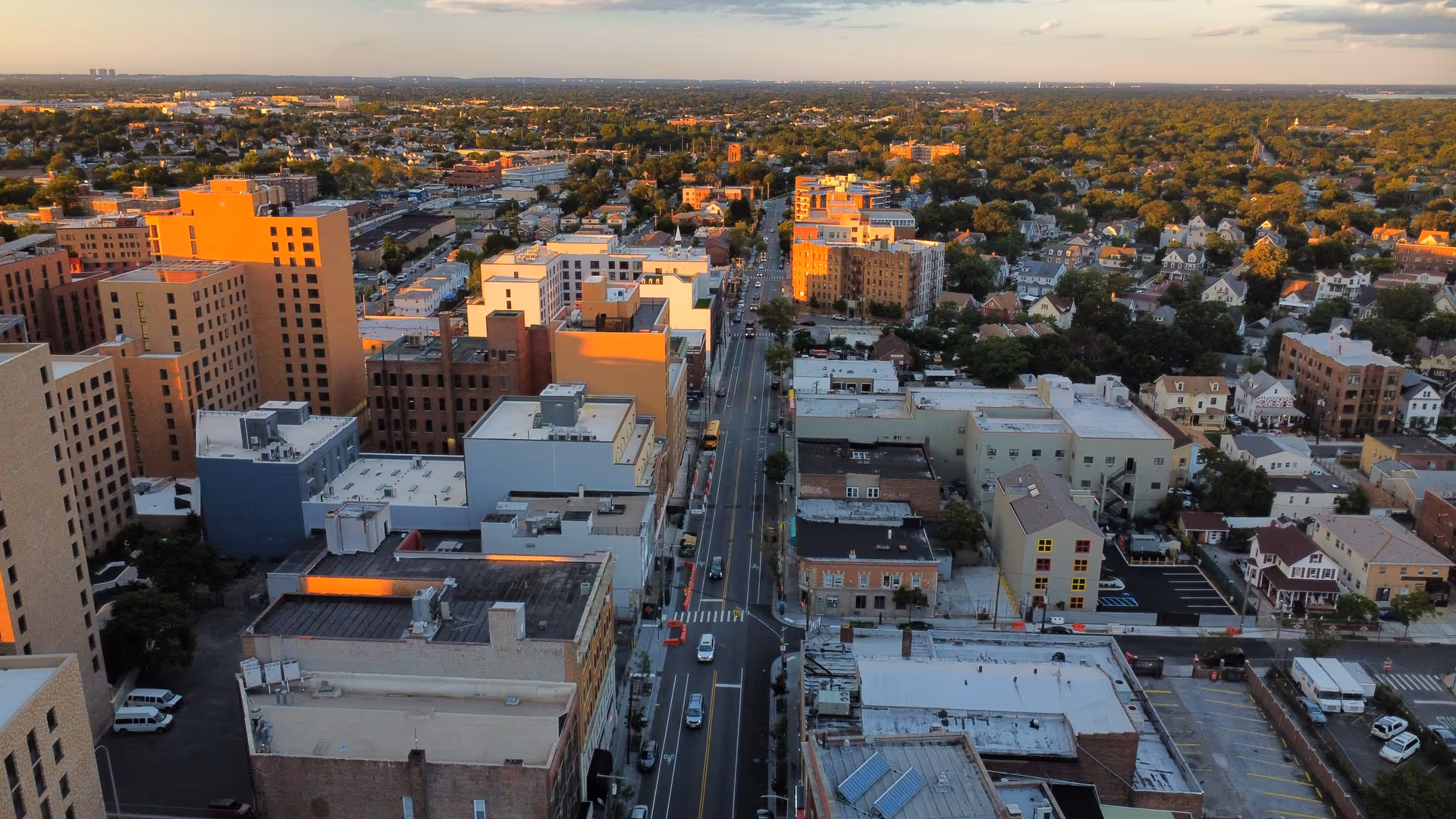 Aerial view of an urban cityscape with tall buildings and streets at sunset.