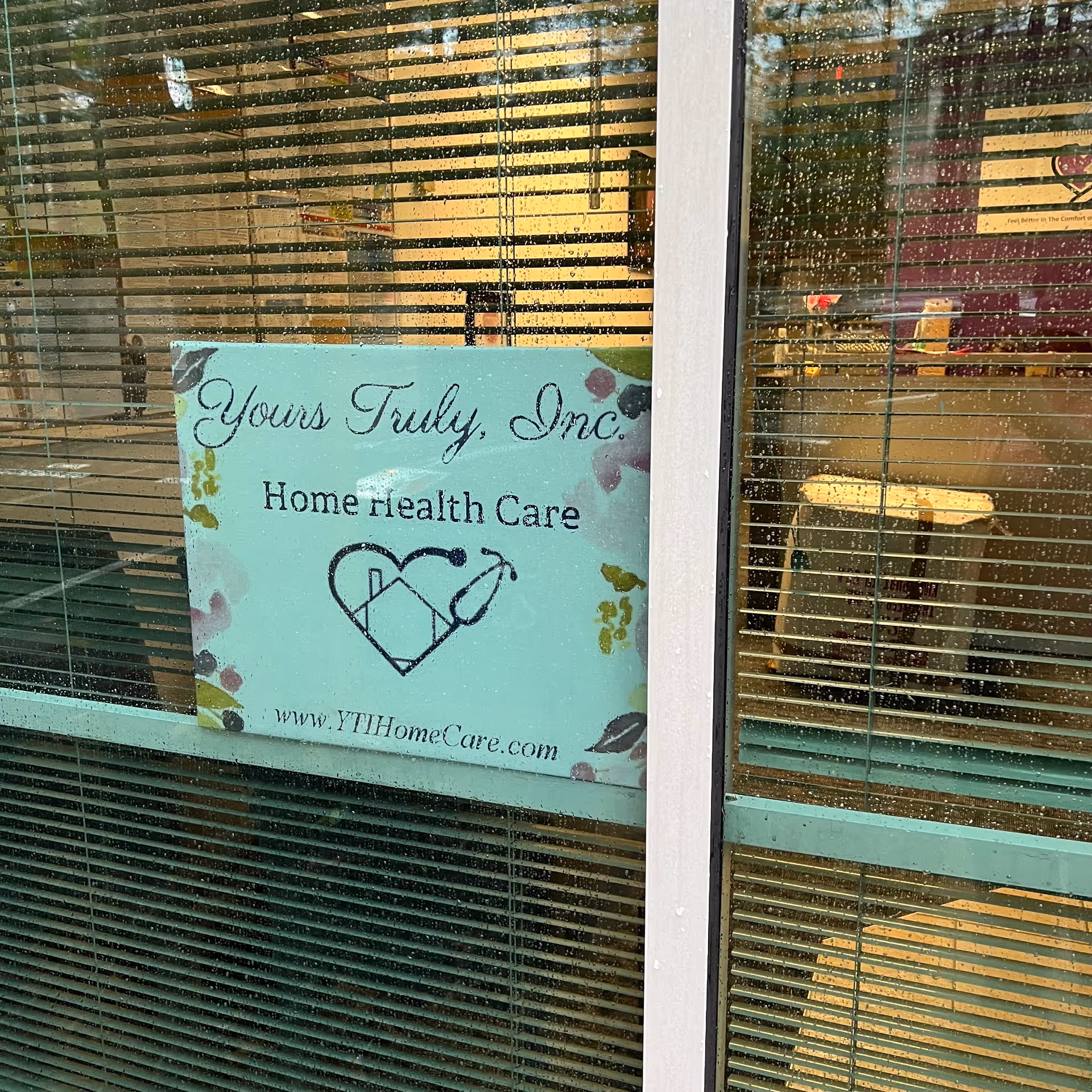 Exterior glass door with striped blinds and a sign for Yours Truly, Inc. Home Health Care.