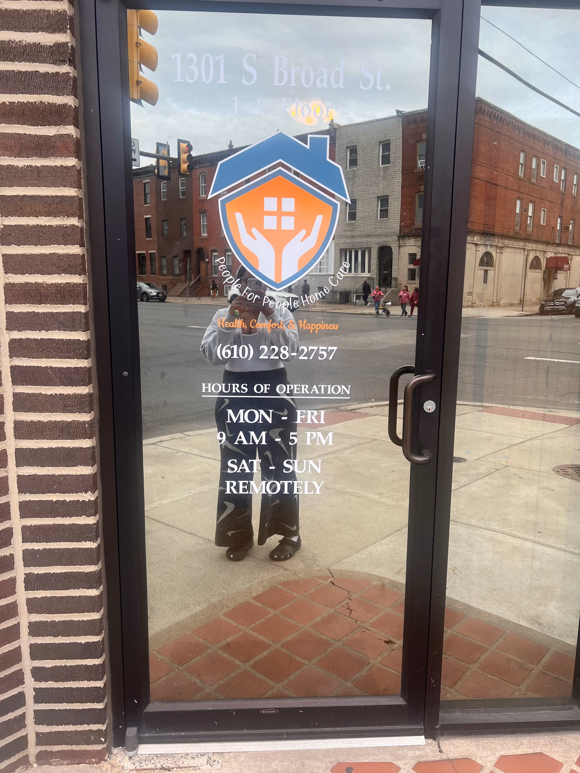 Glass entrance door displaying People for People Home Care logo with street reflection.
