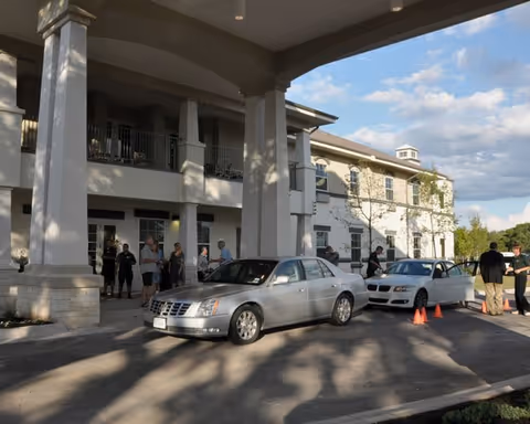 Entrance of Truewood by Merrill Georgetown with parked cars and residents.
