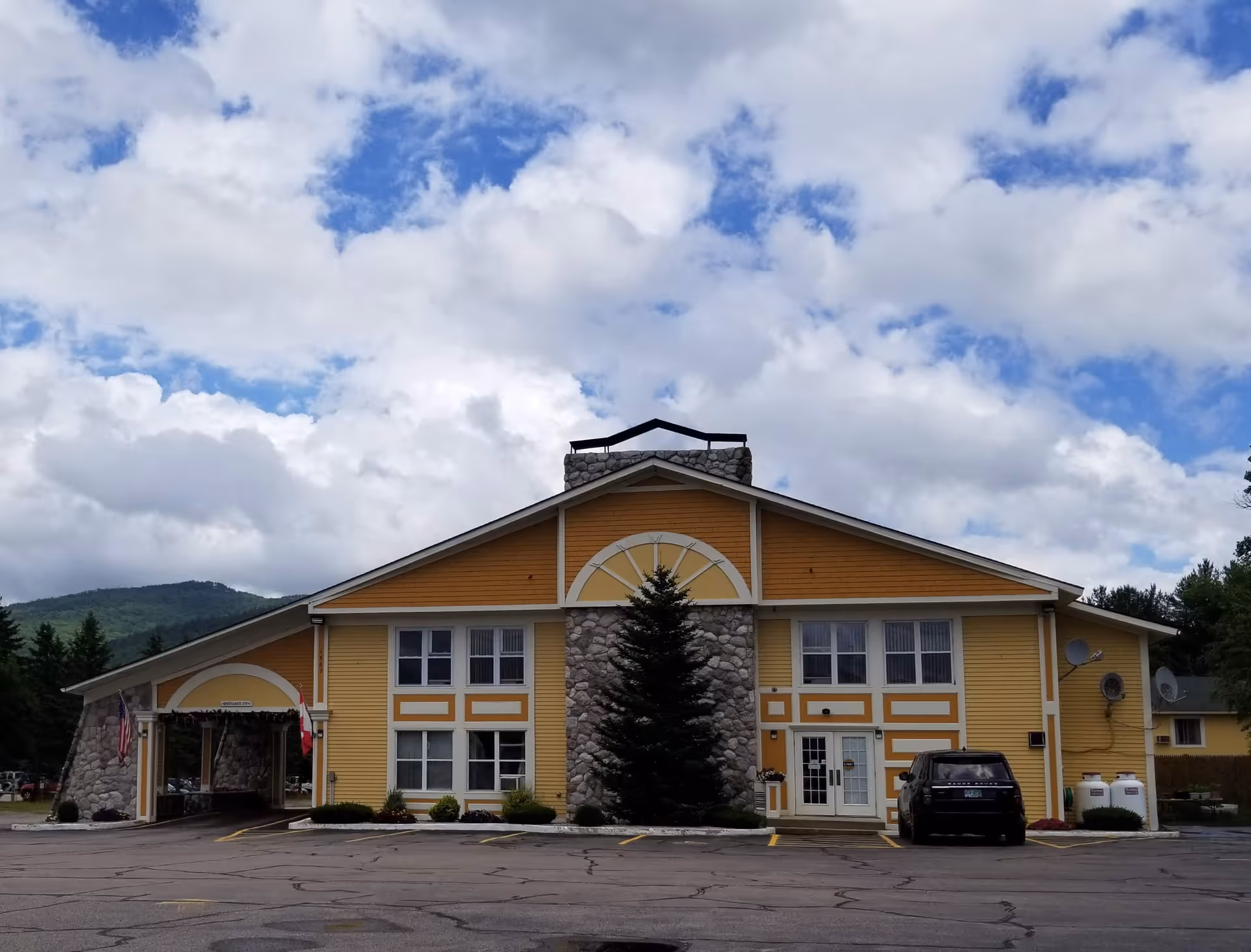 Yellow two-story facility with stone accents and a parking lot in front.