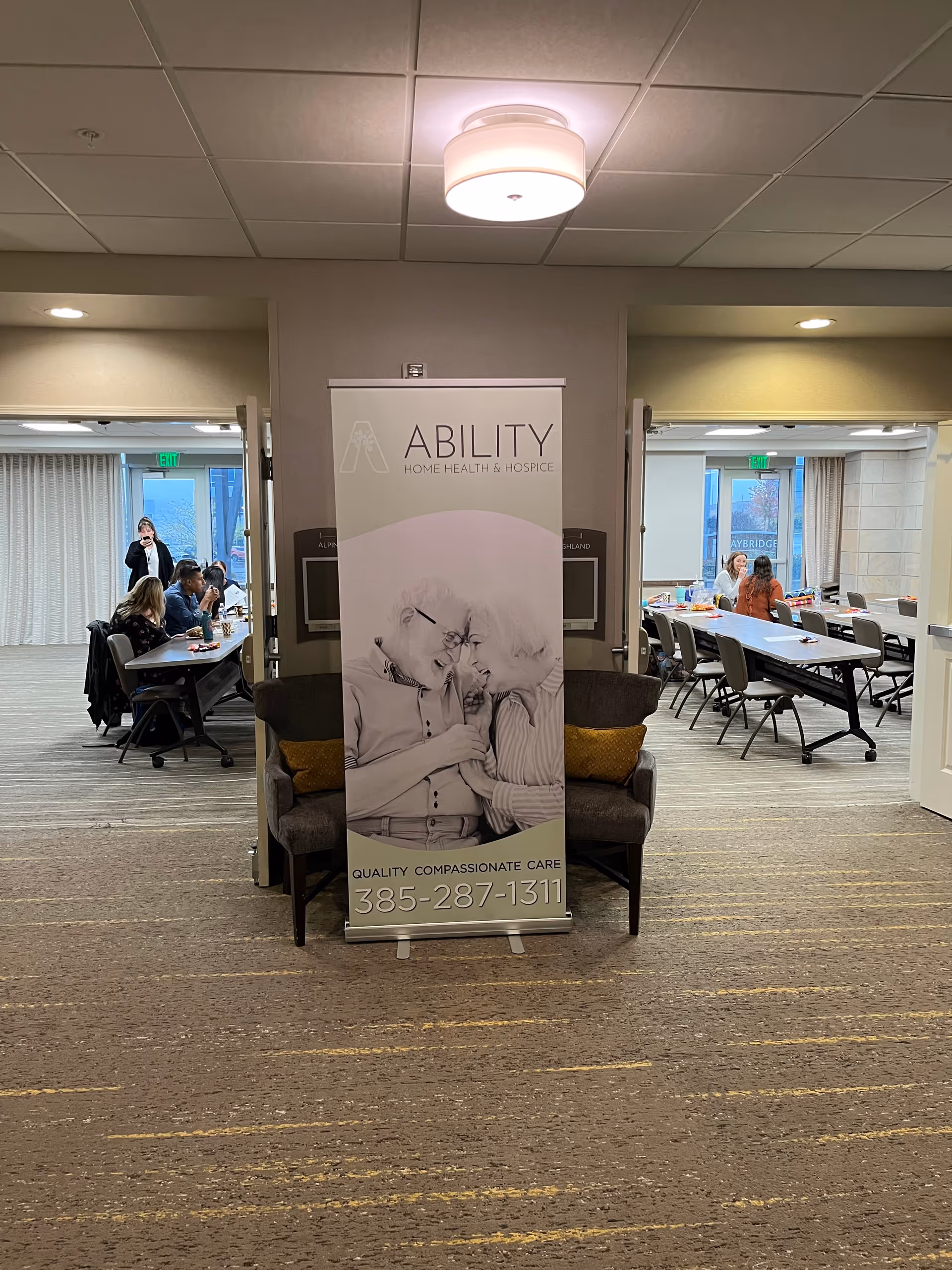 Indoor lobby with a banner for Ability Home Health and Hospice and people seated nearby