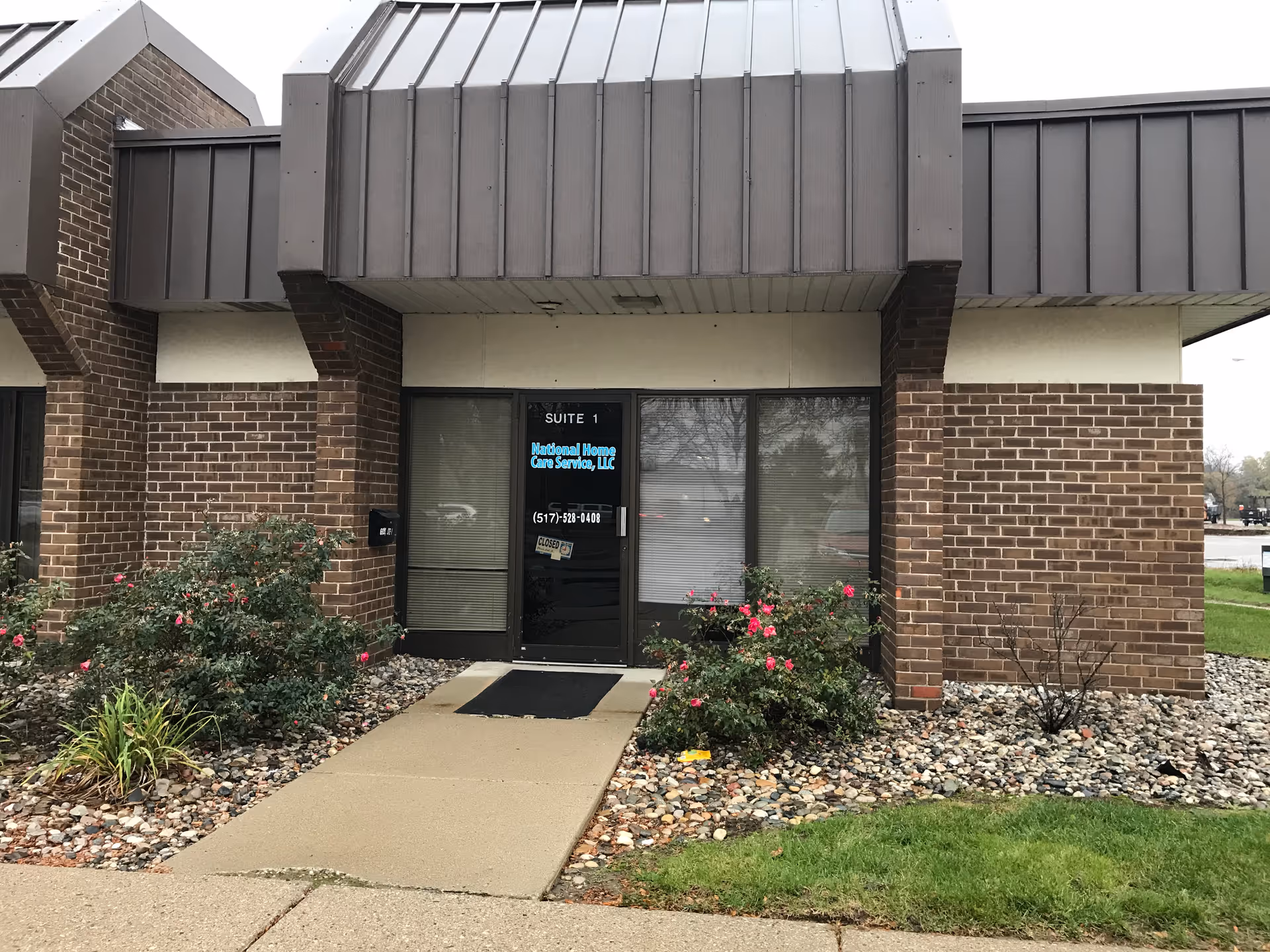 Exterior view of National Home Care Service entrance with glass doors and landscaped walkway.