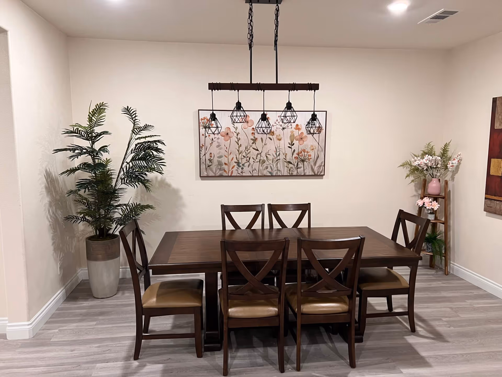 A wooden dining table with six chairs in a well-lit, decorative dining room.