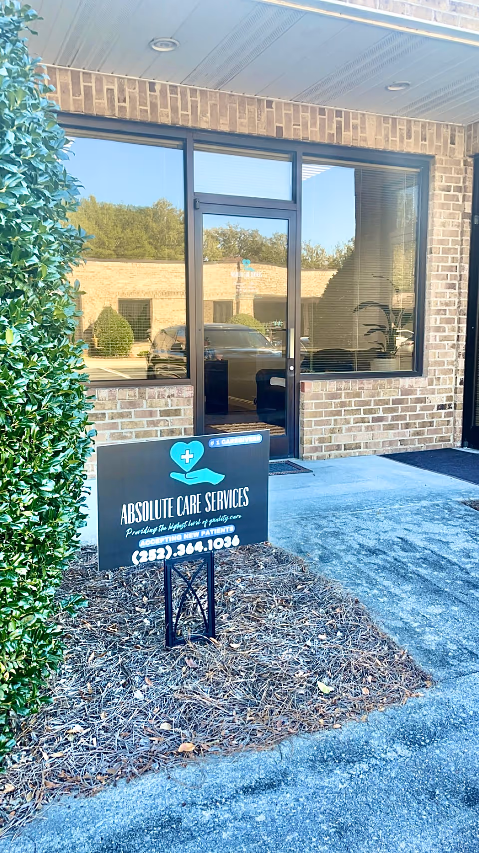 Exterior view of Absolute Care Services entrance with a sign by a brick building.