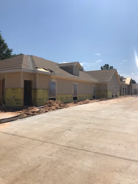 Under construction, exterior of a senior living facility with beige siding and sand piles.