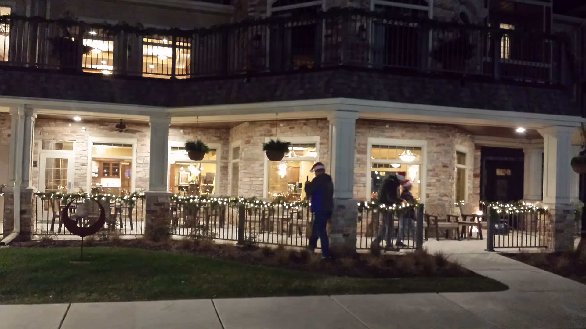 Night exterior of New Perspective Senior Living building with a lit porch and people walking.
