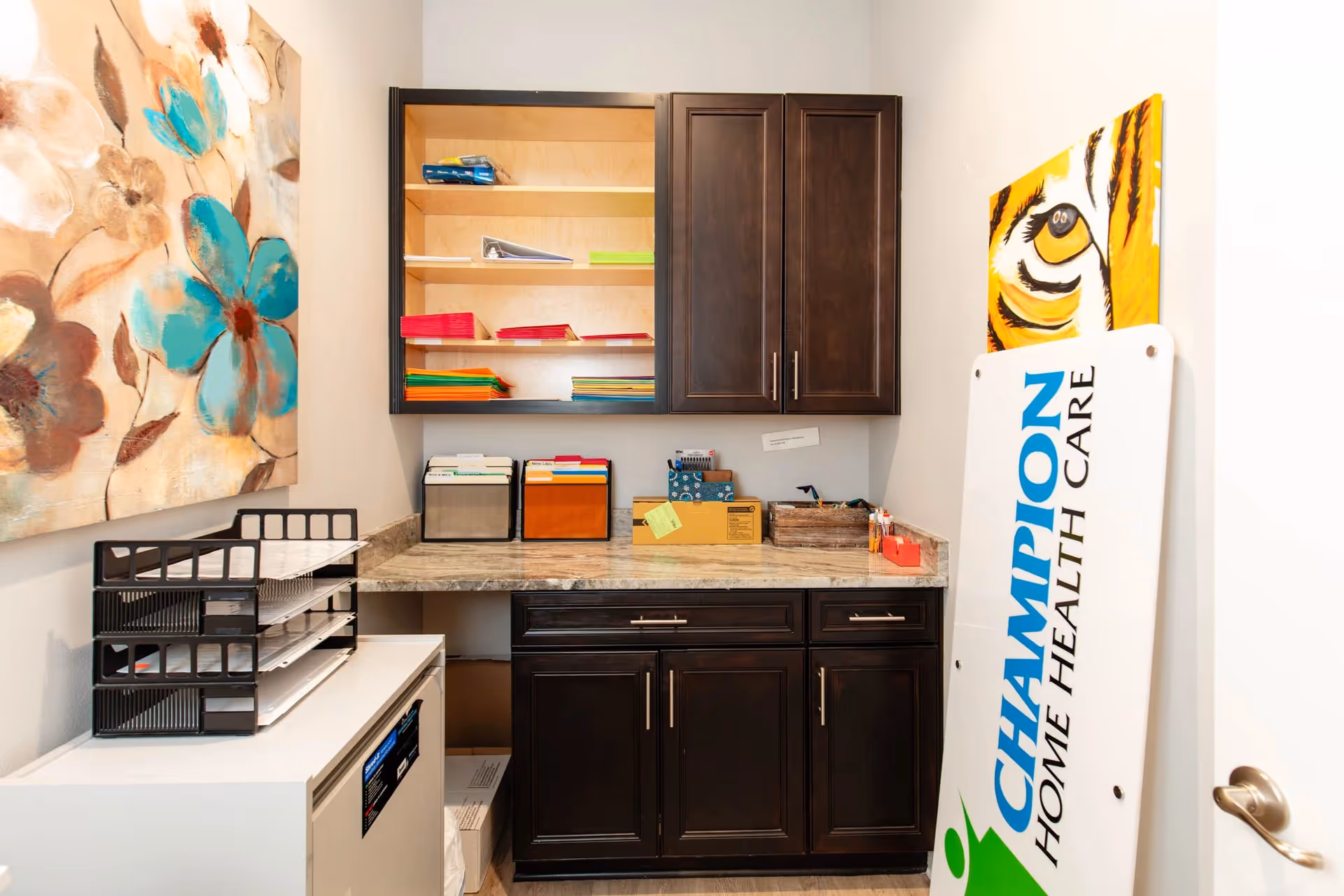 A small interior supply room with dark cabinets, shelves, and a Champion Home Health Care sign.