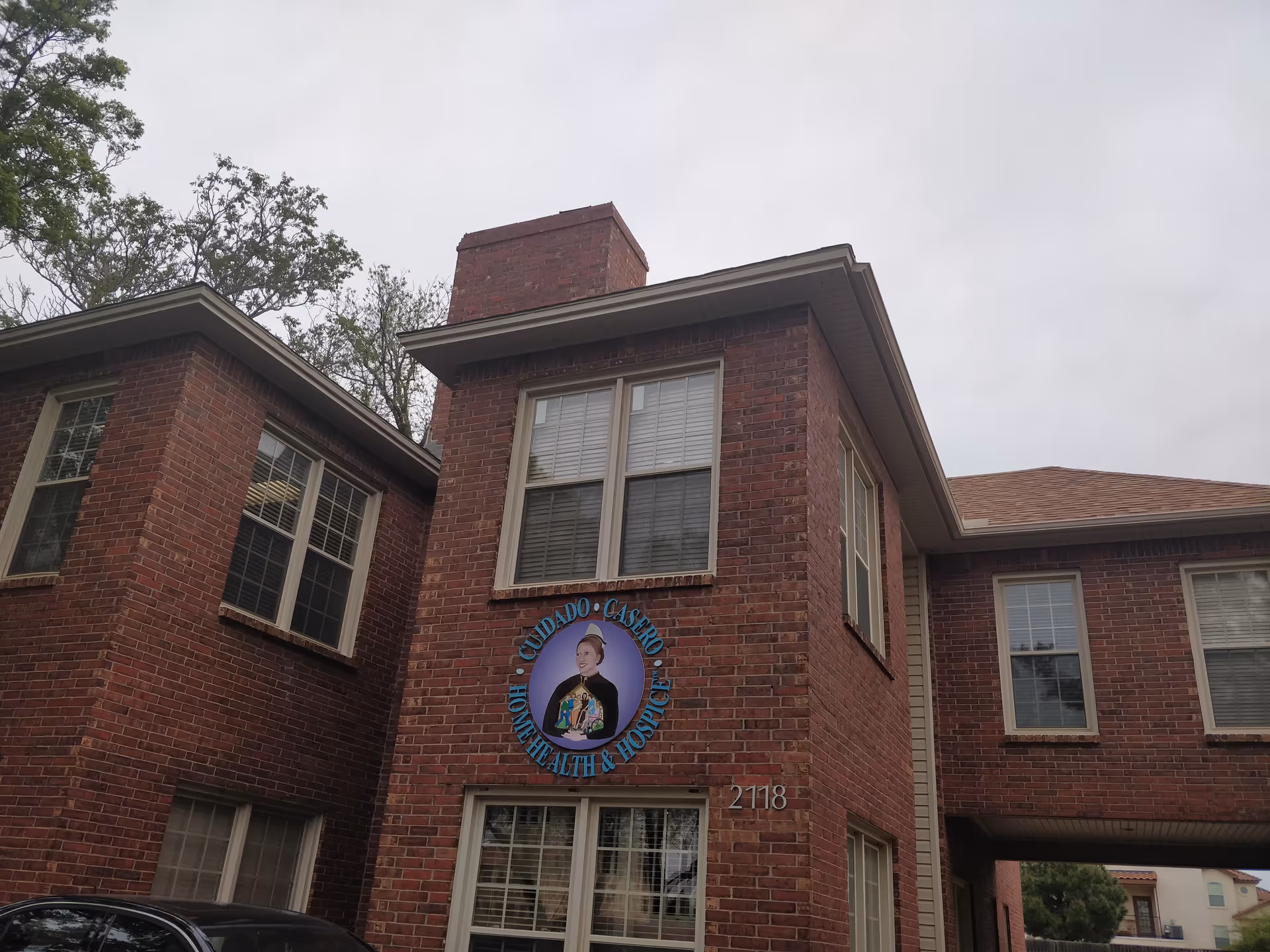 Brick senior living building front with circular Cuidado Casero sign.