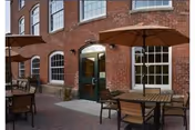 Brick building exterior with arched windows and outdoor patio seating under umbrellas.