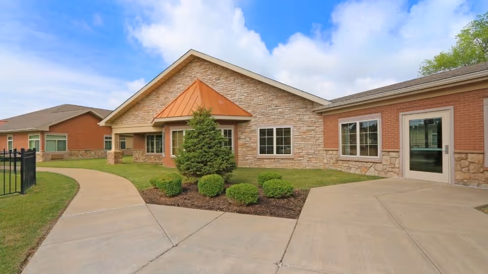 Exterior view of Life Care Center of Florissant, brick and stone entrance with landscaped path.