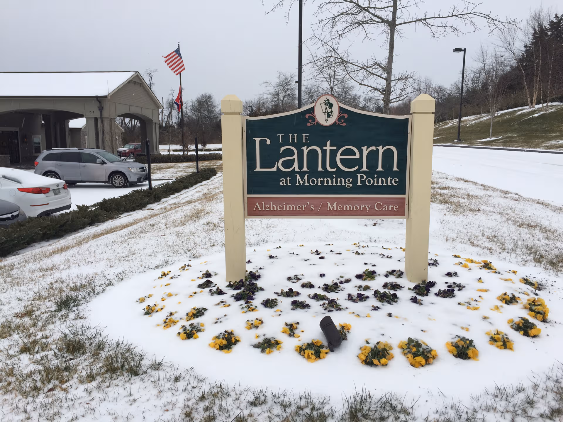 Exterior view of The Lantern at Morning Pointe sign with snow-covered grounds and parked cars.