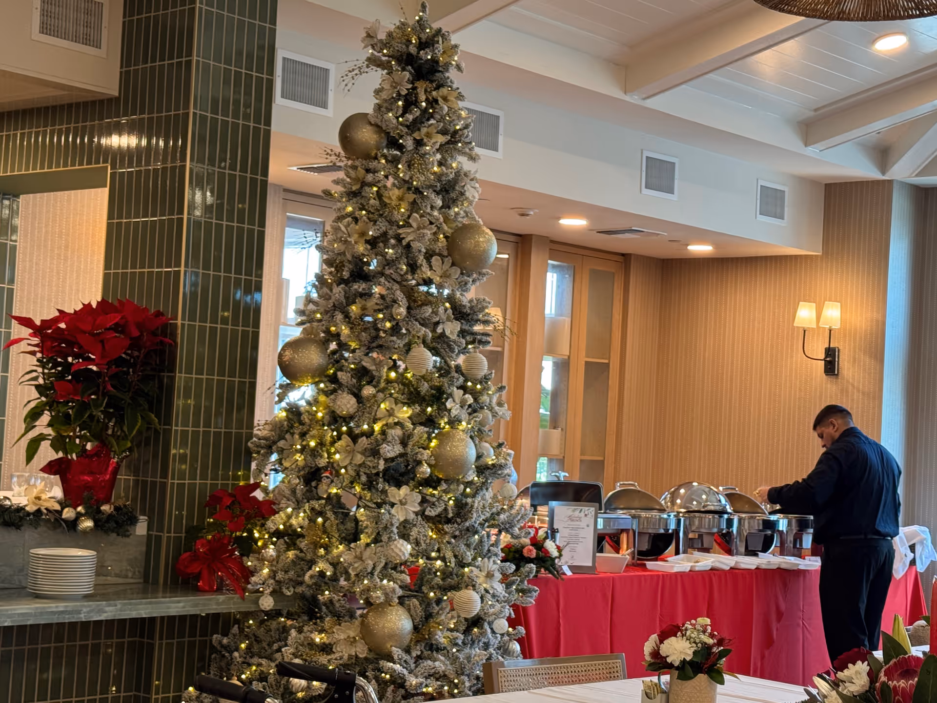 A festive dining area with a tall Christmas tree and a buffet setup.