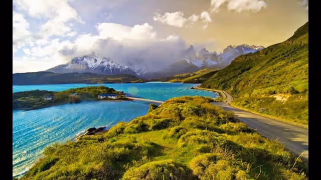 Scenic coastal landscape with turquoise water, green hills, and distant mountains.