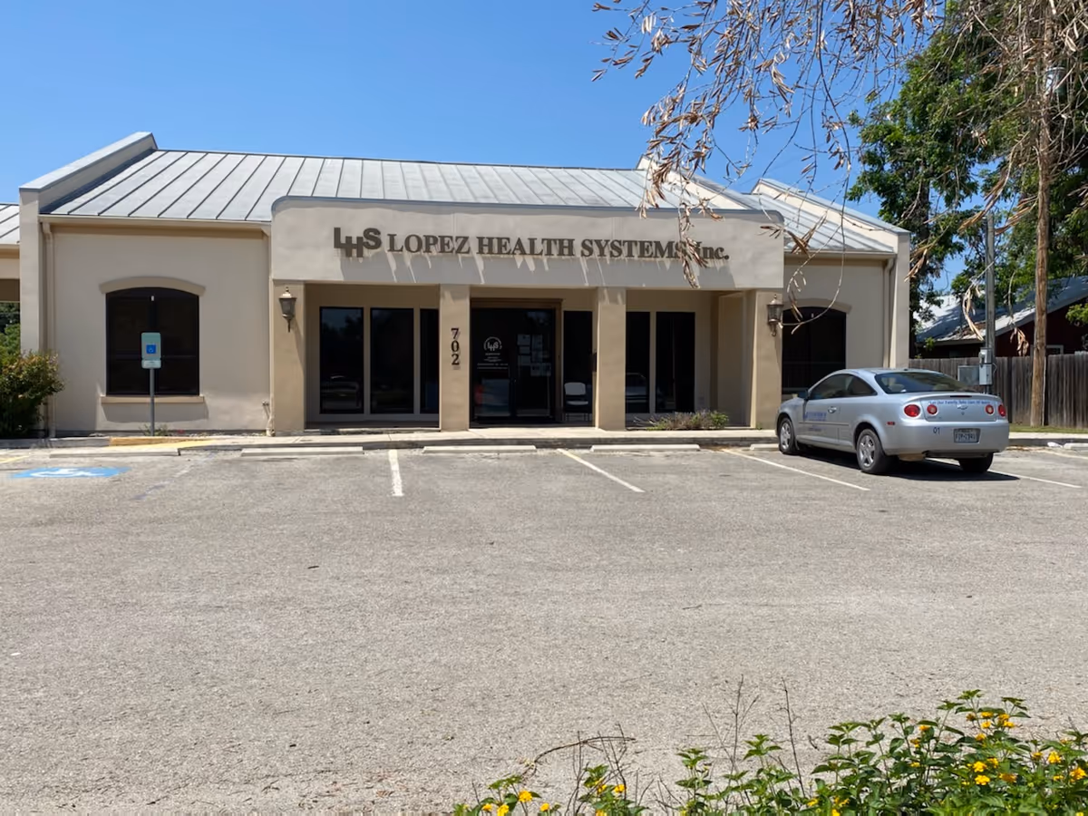 Front view of Lopez Health Systems Inc building with a parked car in the lot.