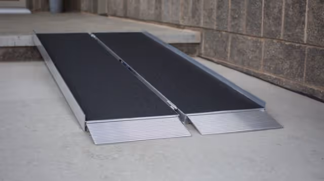 Exterior entrance ramp with black surface and metal edging.