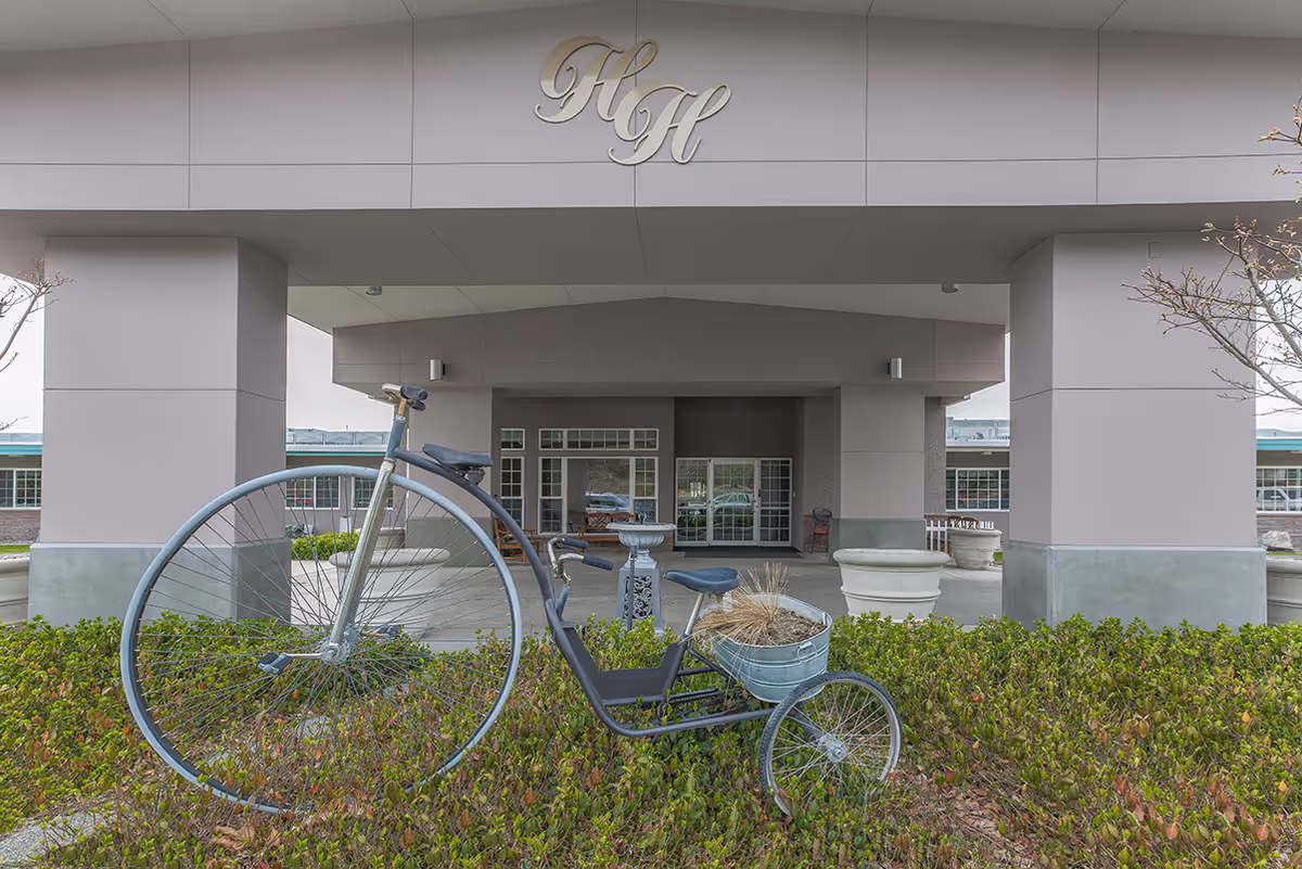 Front view of Regency Harmony House Rehab & Nursing entrance; a vintage bicycle sits near hedges.