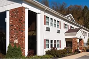 Front exterior of a white-and-brick senior living center with a walkway and windows.