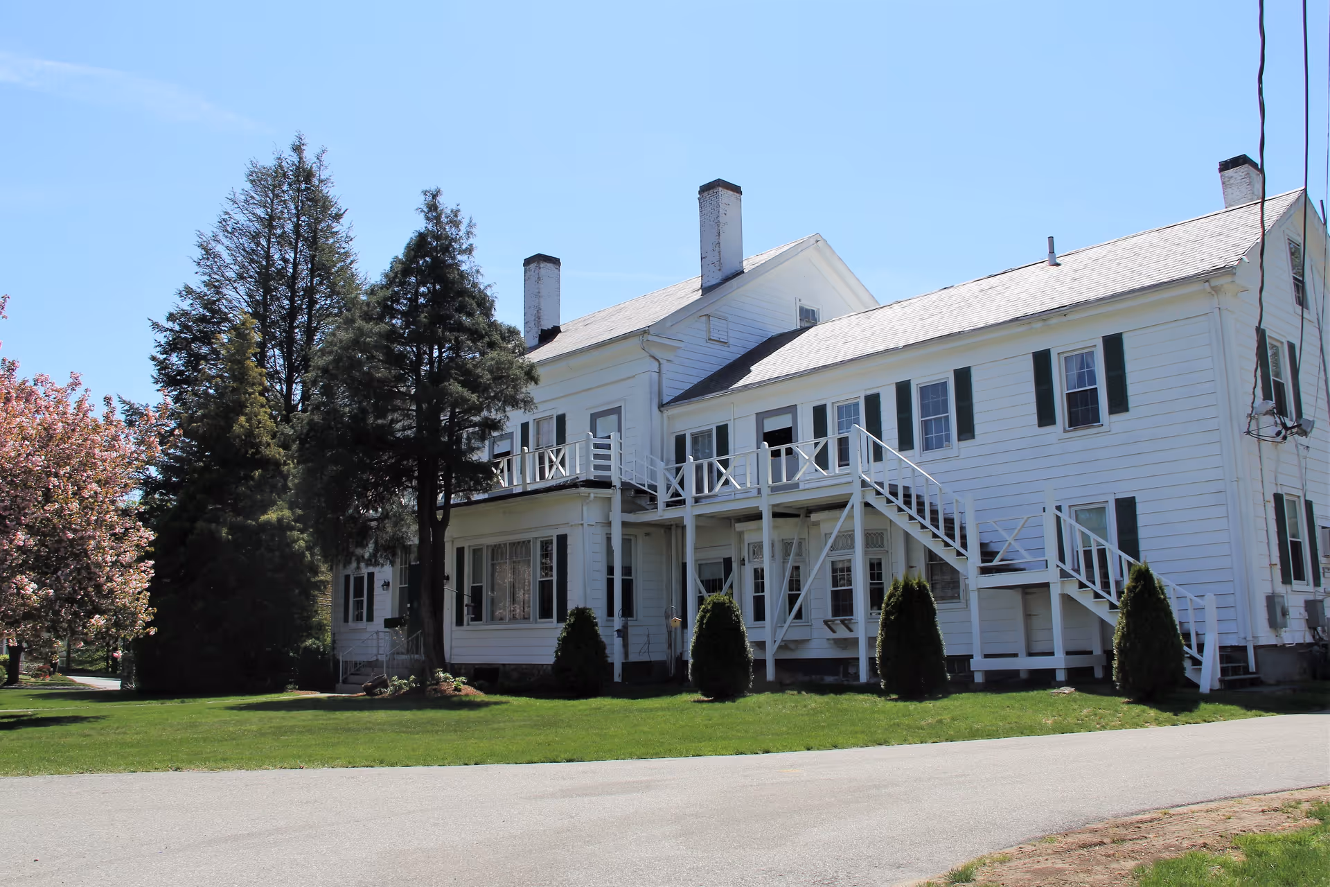 White two-story Bridgewater Skilled Nursing & Rehab building with exterior stairs and a green lawn.