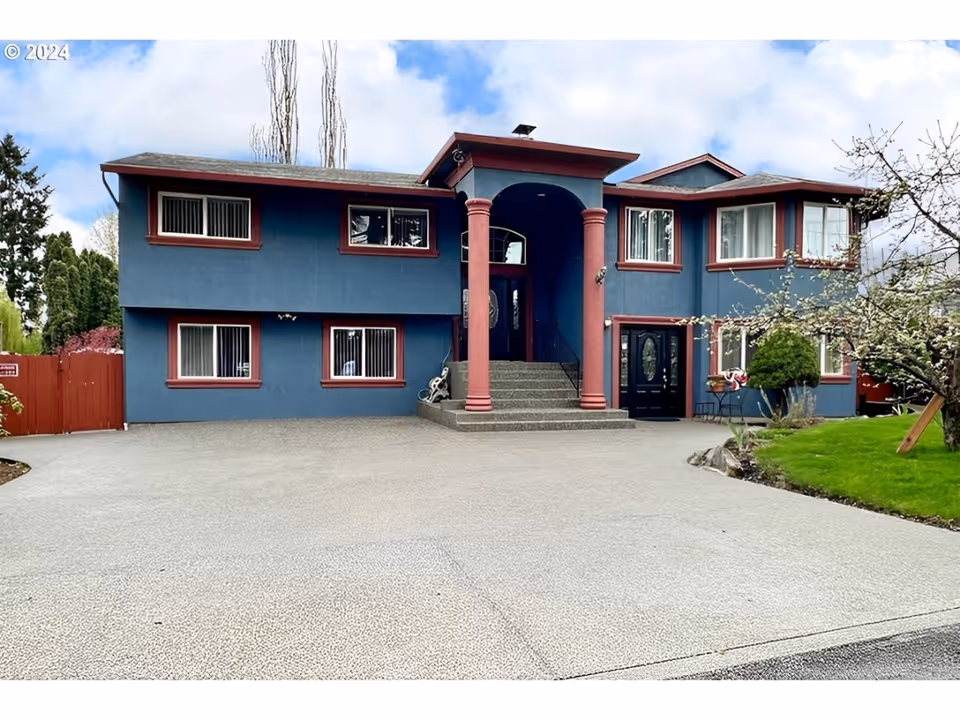 Blue two-story adult family home with pink columns and a large front driveway.