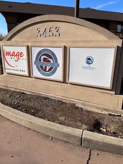 Exterior sign on a building shows address 3453 and three business logos.