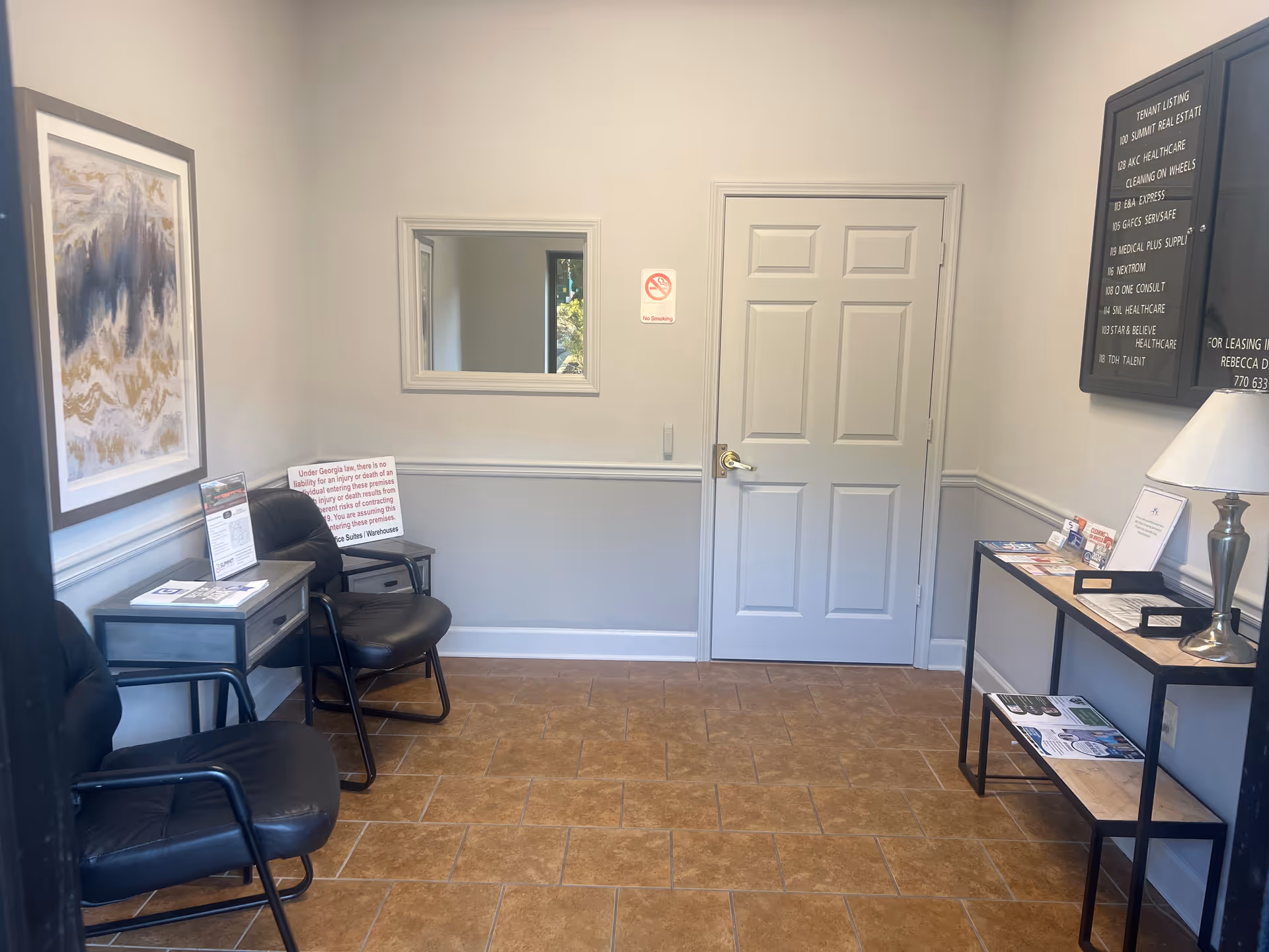 A small waiting area with black chairs, a door, and a bulletin board.