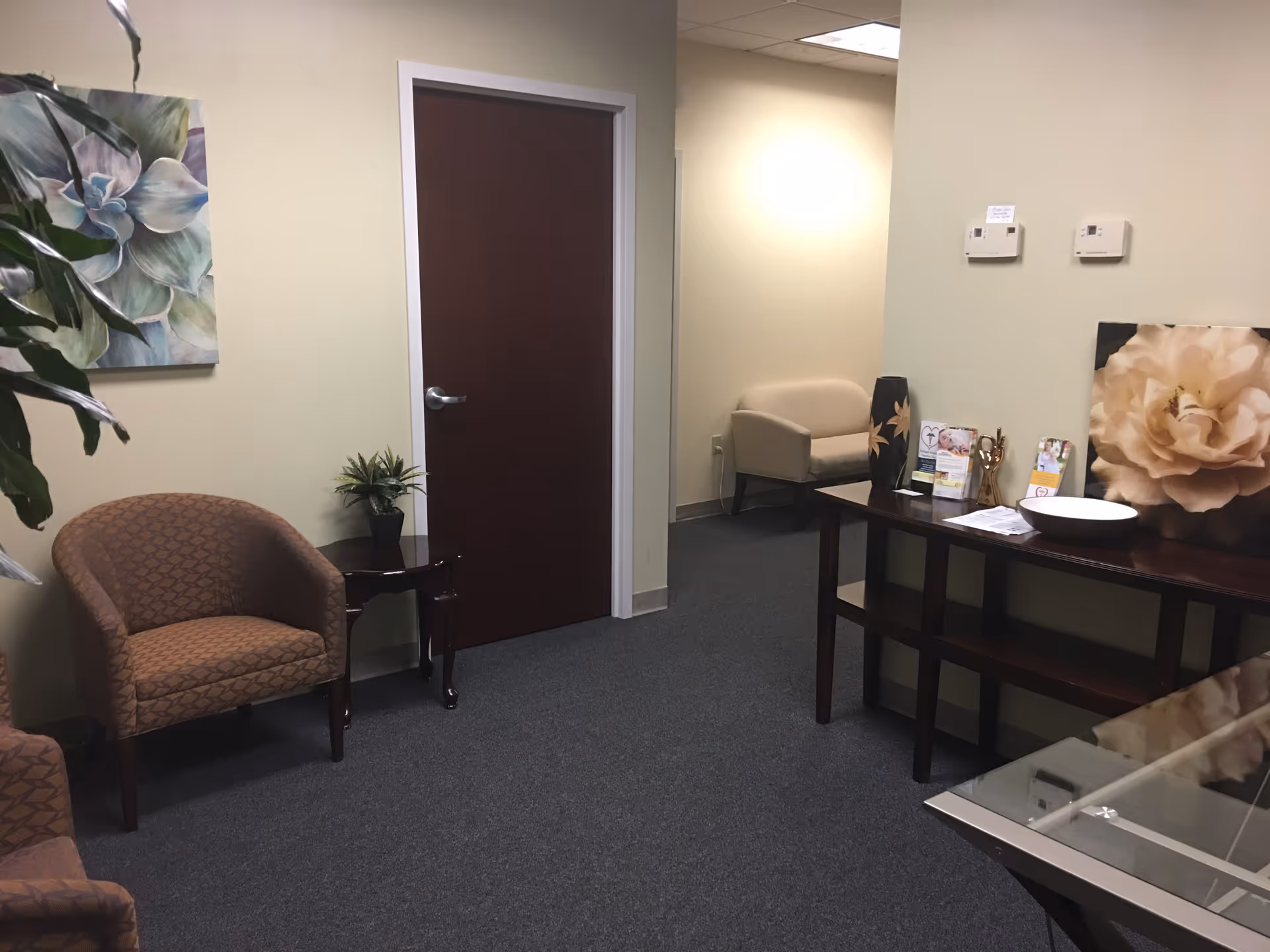Waiting area inside a senior care facility with chairs, a desk, and decorative artwork.